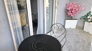 Un patio con una mesa redonda y sillas, una puerta corrediza de vidrio y plantas en macetas.