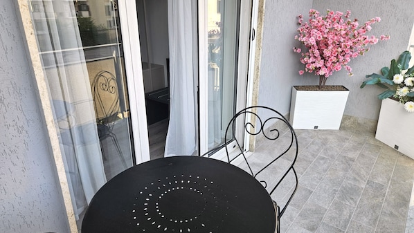 A patio with a round table and chairs, a sliding glass door, and potted plants.