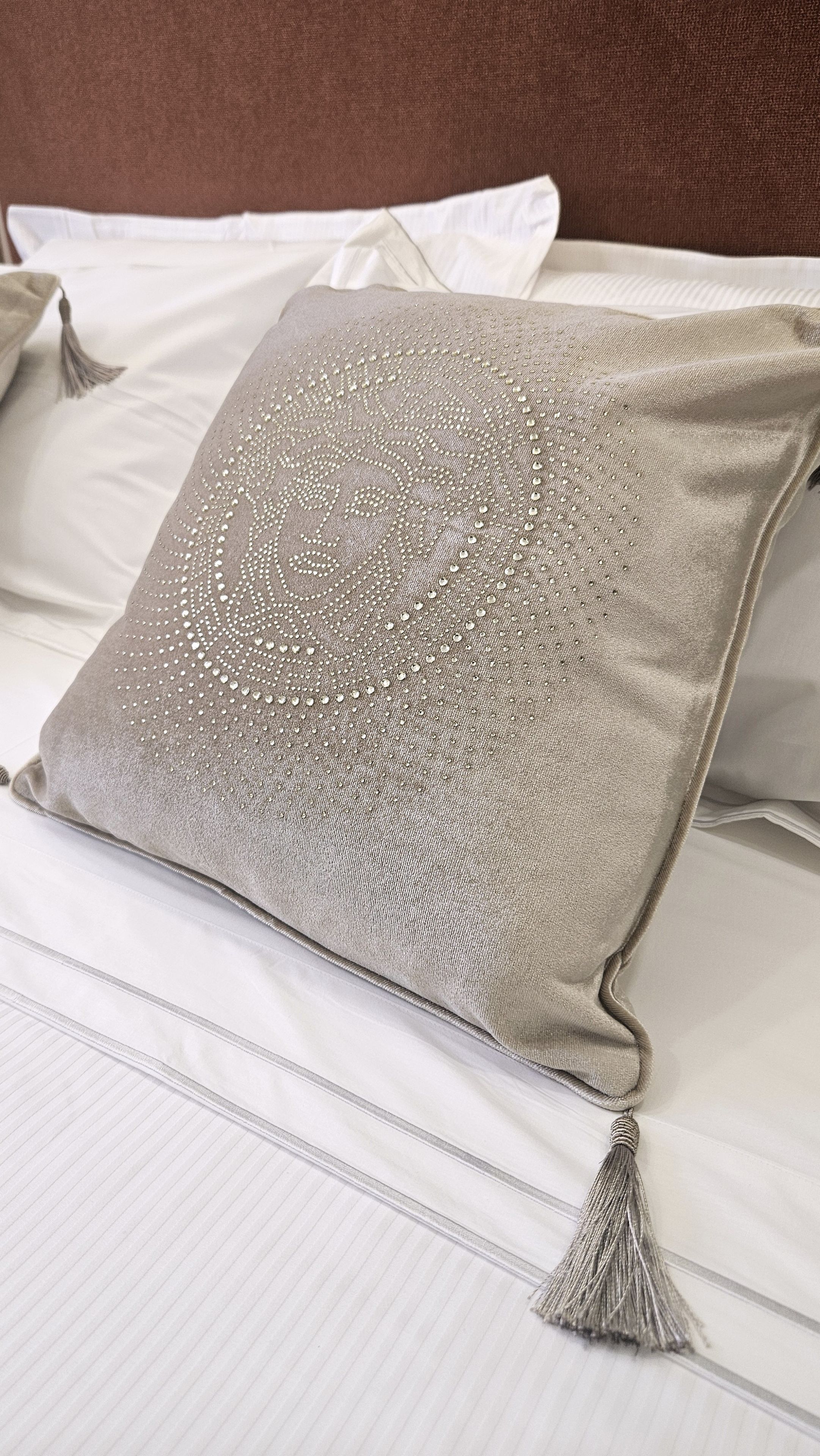 Una cama con un cojín de textura y borlas.