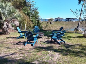 A patio area with outdoor seating and a view of a distant building. -  Lake Home, Private Pier, Smoker/Grill included. Sunrises in your backyard. (Lake Waccamaw)
