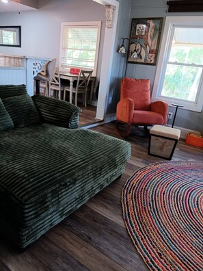 A cozy living room with a green sofa, a colorful rug, and a red chair. -  Lake Home, Private Pier, Smoker/Grill included. Sunrises in your backyard. (Lake Waccamaw)