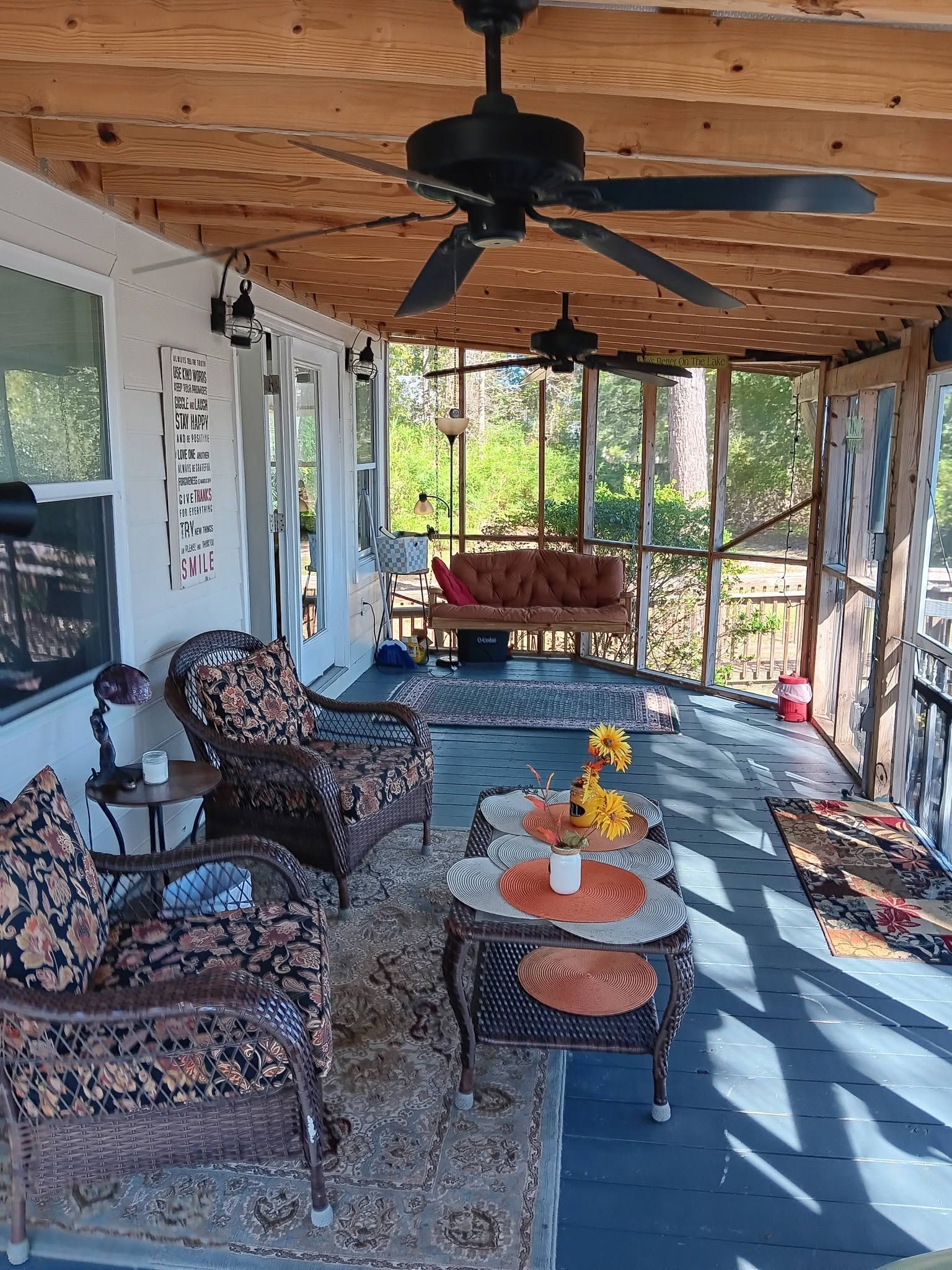 Eine überdachte Veranda mit Korbmöbeln, einem Deckenventilator und Blick ins Freie.