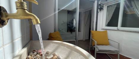 A bathtub filled with seashells and water flowing from a brass faucet.