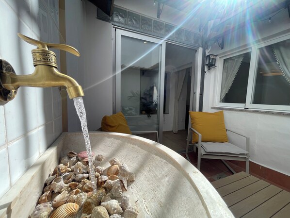 A bathtub filled with seashells and water flowing from a brass faucet.