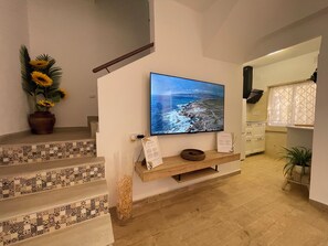 A staircase with patterned tiles, a flat-screen TV on a wall, a potted plant, and a wooden shelf. - Charming Little House (Requena)