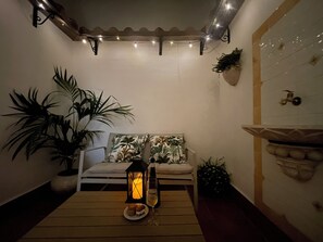 A cozy seating area with a table, a lantern, and a potted plant.