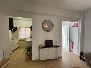 A living room with a radiator, a clock, and a door with a fire extinguisher. - Charming Little House (Requena)