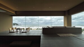 A modern interior with a large window overlooking the ocean, a seating area with cushions, and a minimalist design. - VODASTAY Songjeong (Busan)