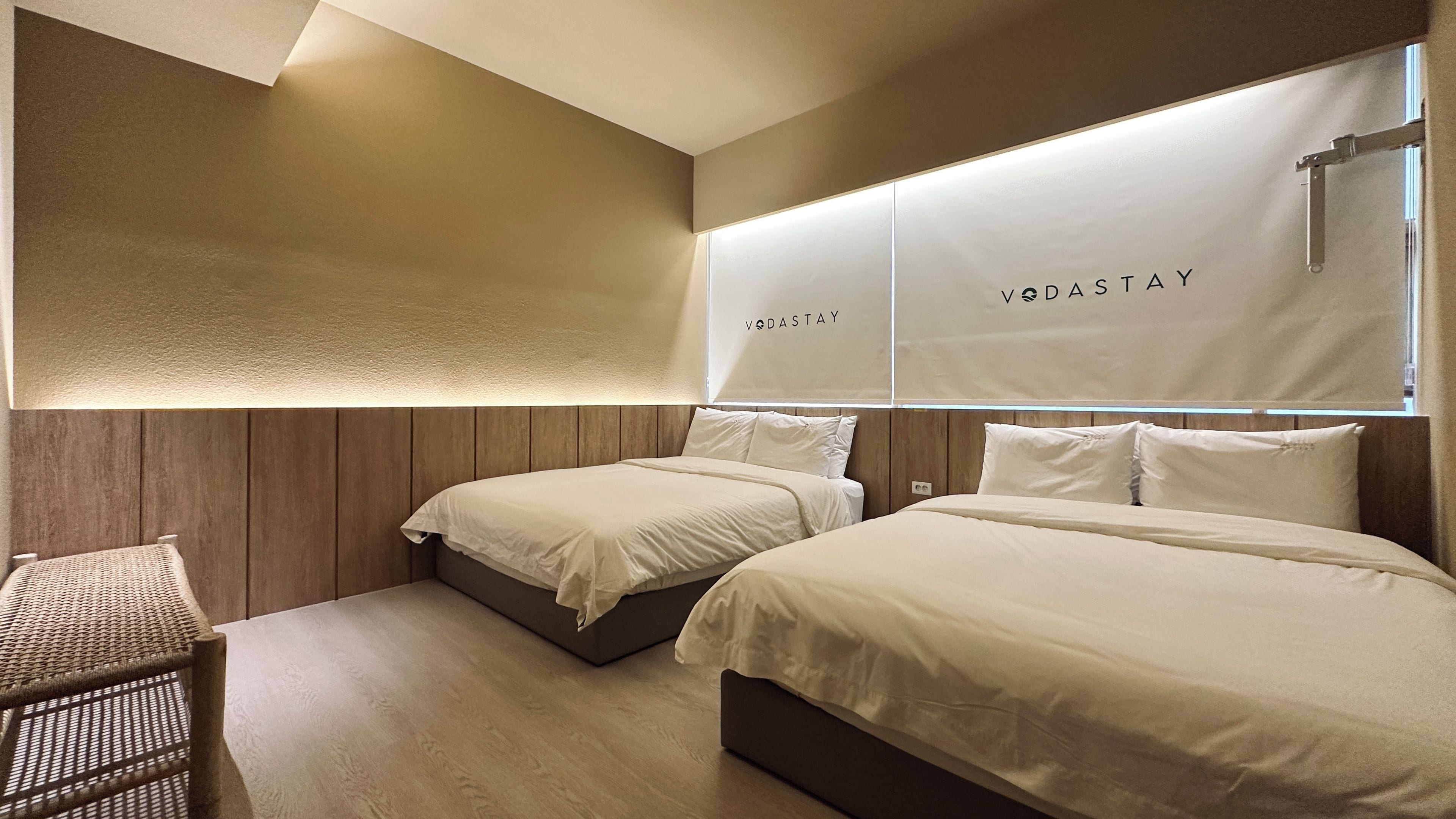 A hotel room with two beds, a small seating area, and a wall-mounted light fixture.