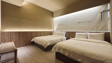 A hotel room with two beds, a small seating area, and a wall-mounted light fixture.