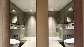 Un baño moderno con un espejo grande, dos lavamanos y un inodoro.