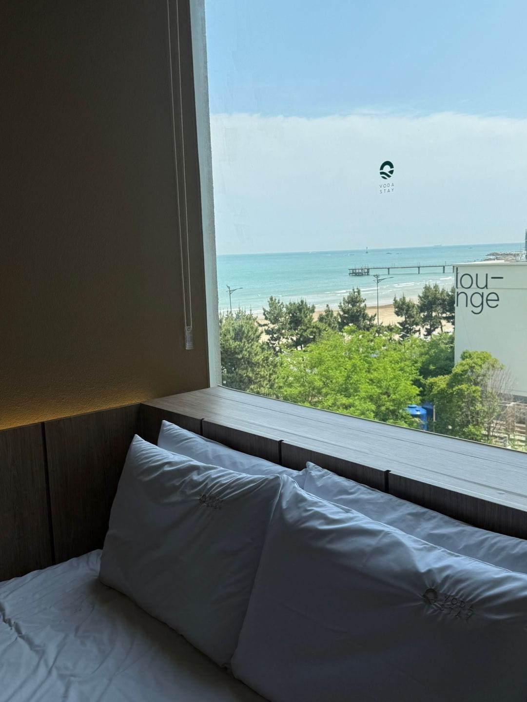 Une chambre d’hôtel avec vue sur la mer, un coin salon et une fenêtre donnant sur la plage et la végétation.