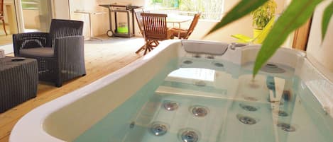Un jacuzzi con terraza de madera, mobiliario de mimbre y vistas al exterior.
