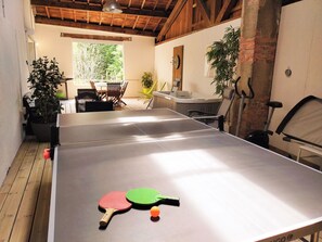 A ping pong table with two paddles and a ball, a dining table with chairs, and a potted plant. - Vrbo Property (Saint-Amant-Tallende)