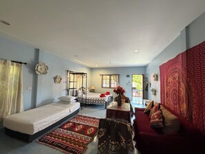 A room with a bed, a sofa, a small table, and a window.