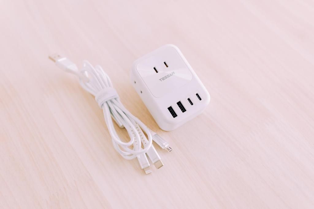 En vit grenuttagslists med flera USB-portar och en kabel, placerad på en ljus träyta.