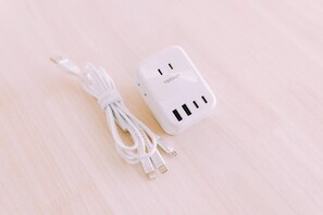 Una regleta blanca con múltiples puertos USB y un cable sobre una superficie de madera clara.