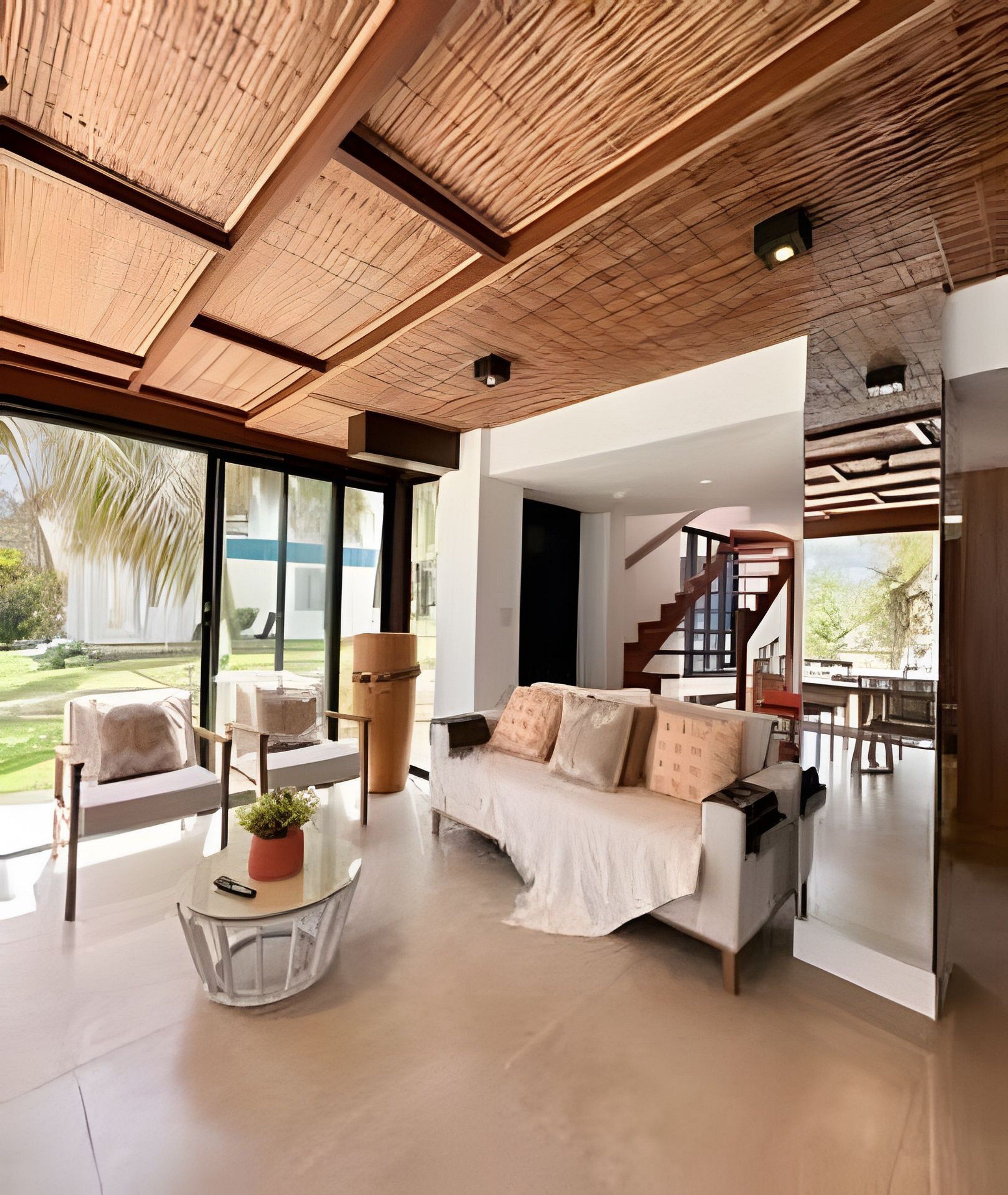 A modern living room with a sofa, chairs, and a coffee table. There is a staircase leading to an upper level.
