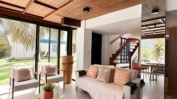 A modern living room with a sofa, chairs, and a coffee table. There is a staircase leading to an upper level.