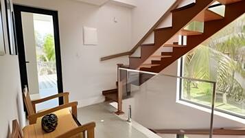 Interior moderno com escada, um banco e vista para o verde lá fora.