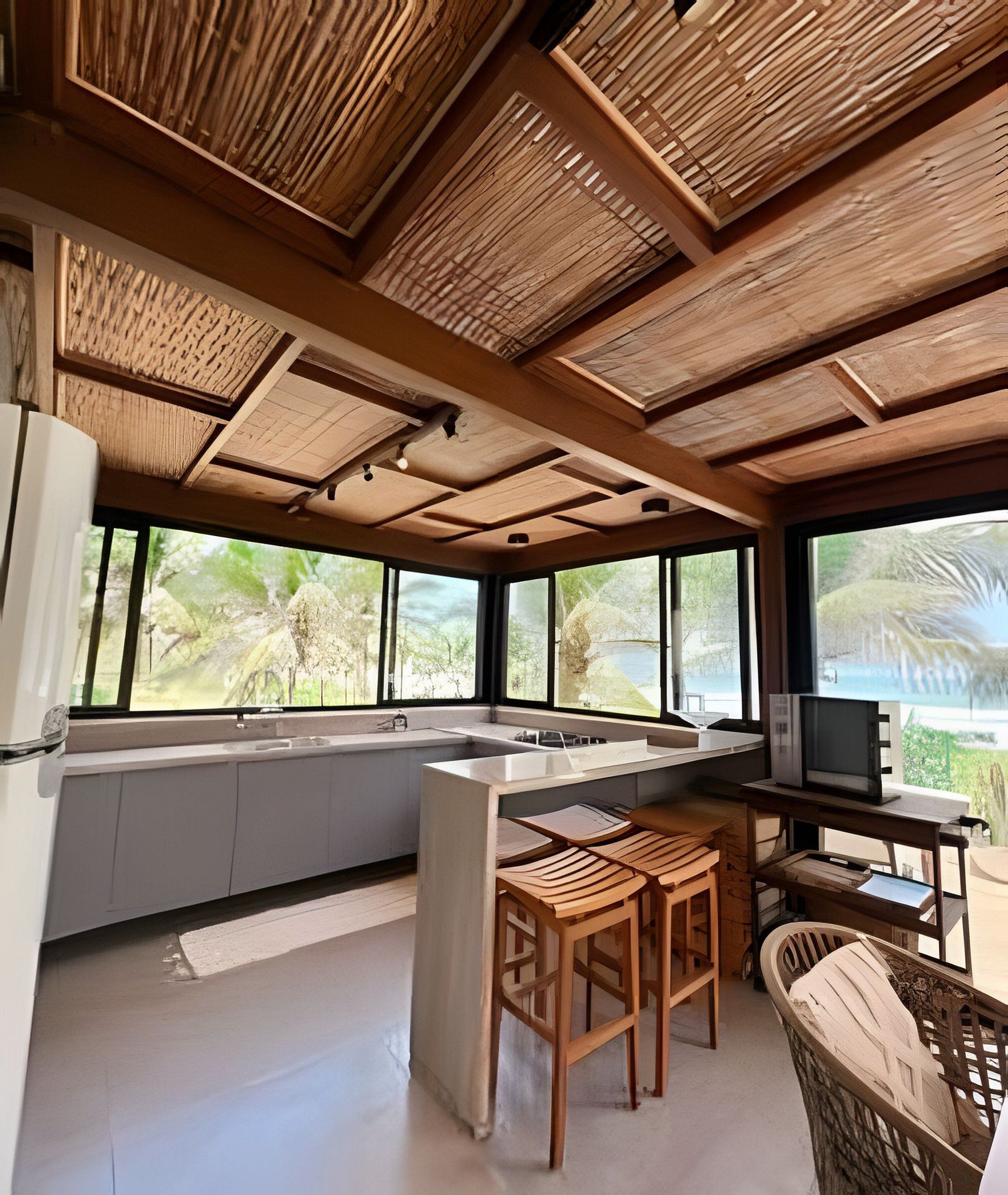 A modern kitchen with a large island, wooden ceiling, and large windows with a view of greenery.