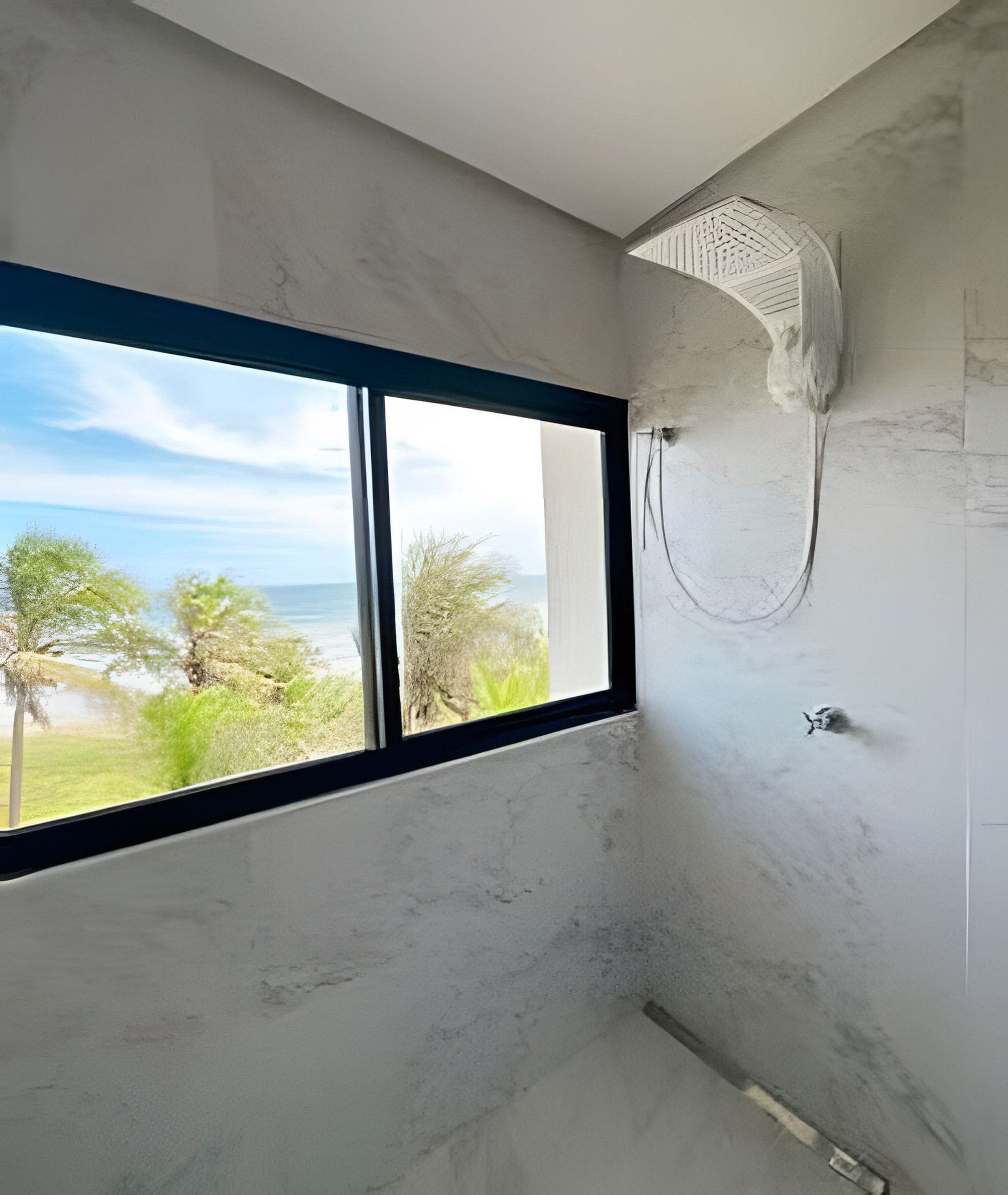 Ein Badezimmer mit großem Fenster, Dusche und Meerblick.