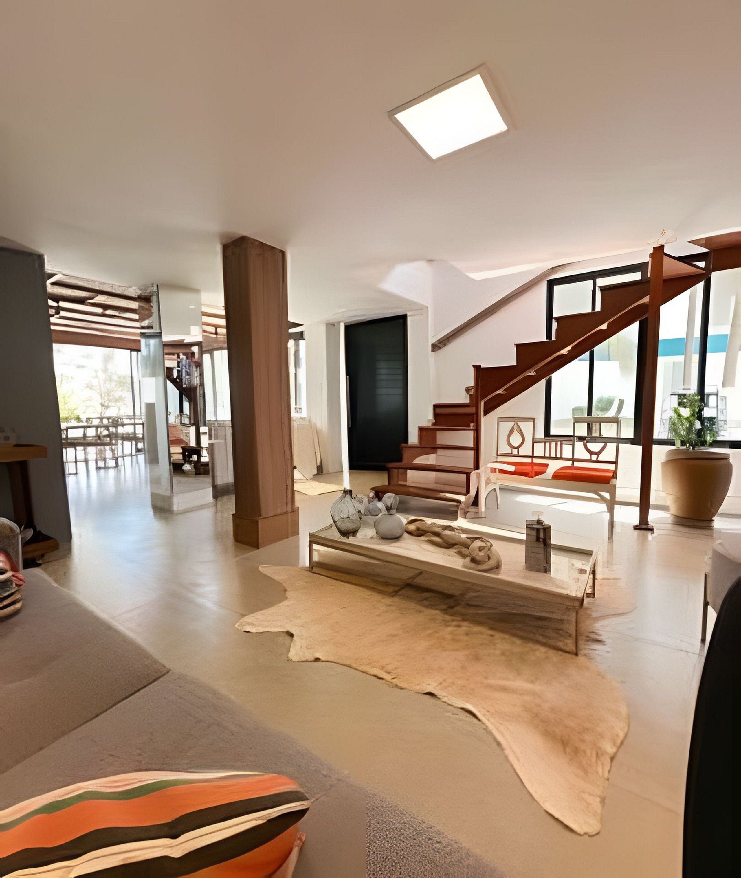Ein modernes Wohnzimmer mit Treppe, großem Fenster und Holzboden.