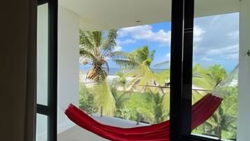 A room with a large window overlooking a coastal landscape with palm trees and a clear sky.