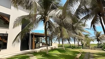 A modern building with a glass facade, surrounded by palm trees and a clear sky.