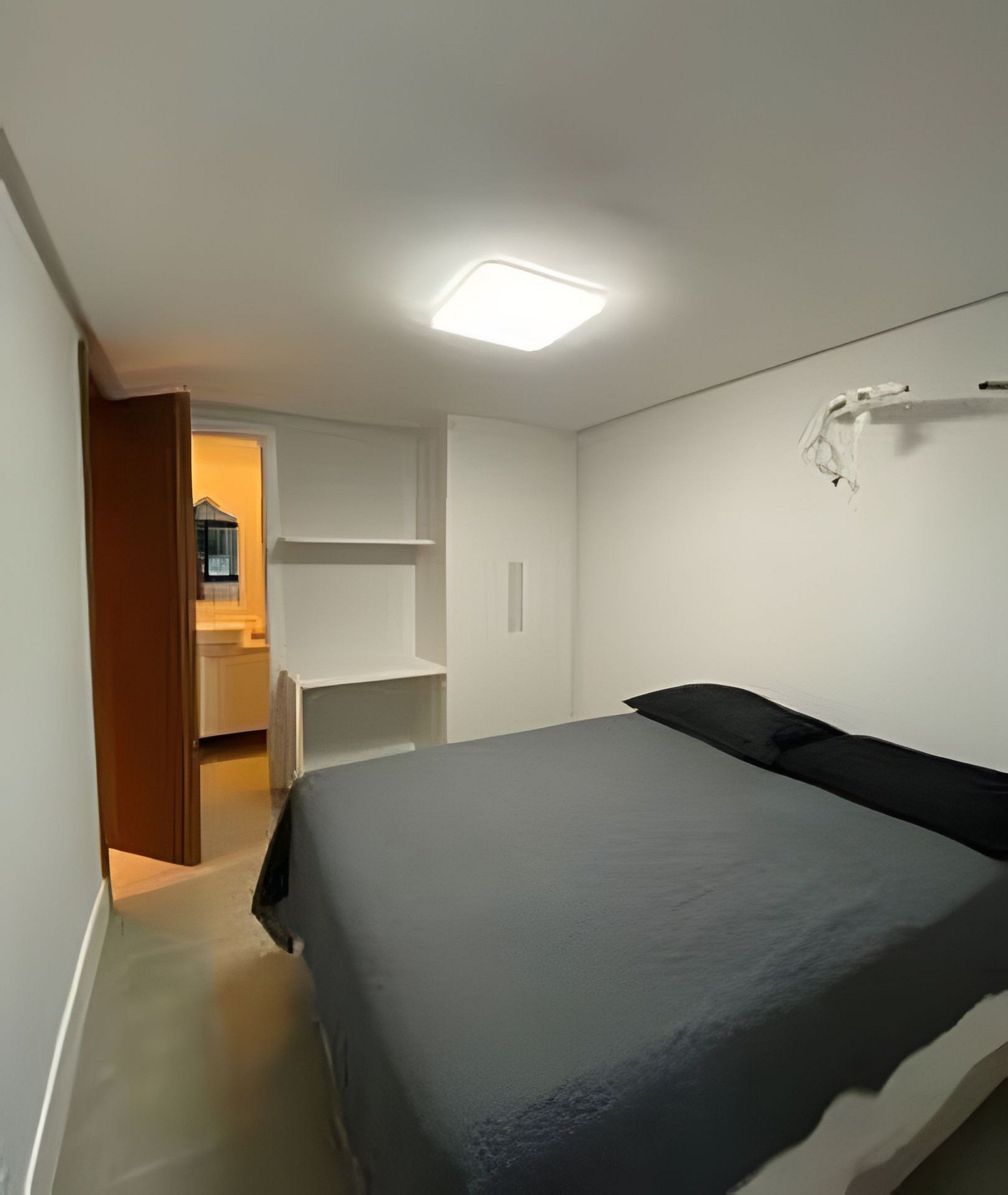 A bedroom with a bed, a wardrobe, and a door leading to a bathroom.