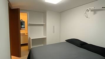 A bedroom with a bed, a wardrobe, and a door leading to a bathroom.
