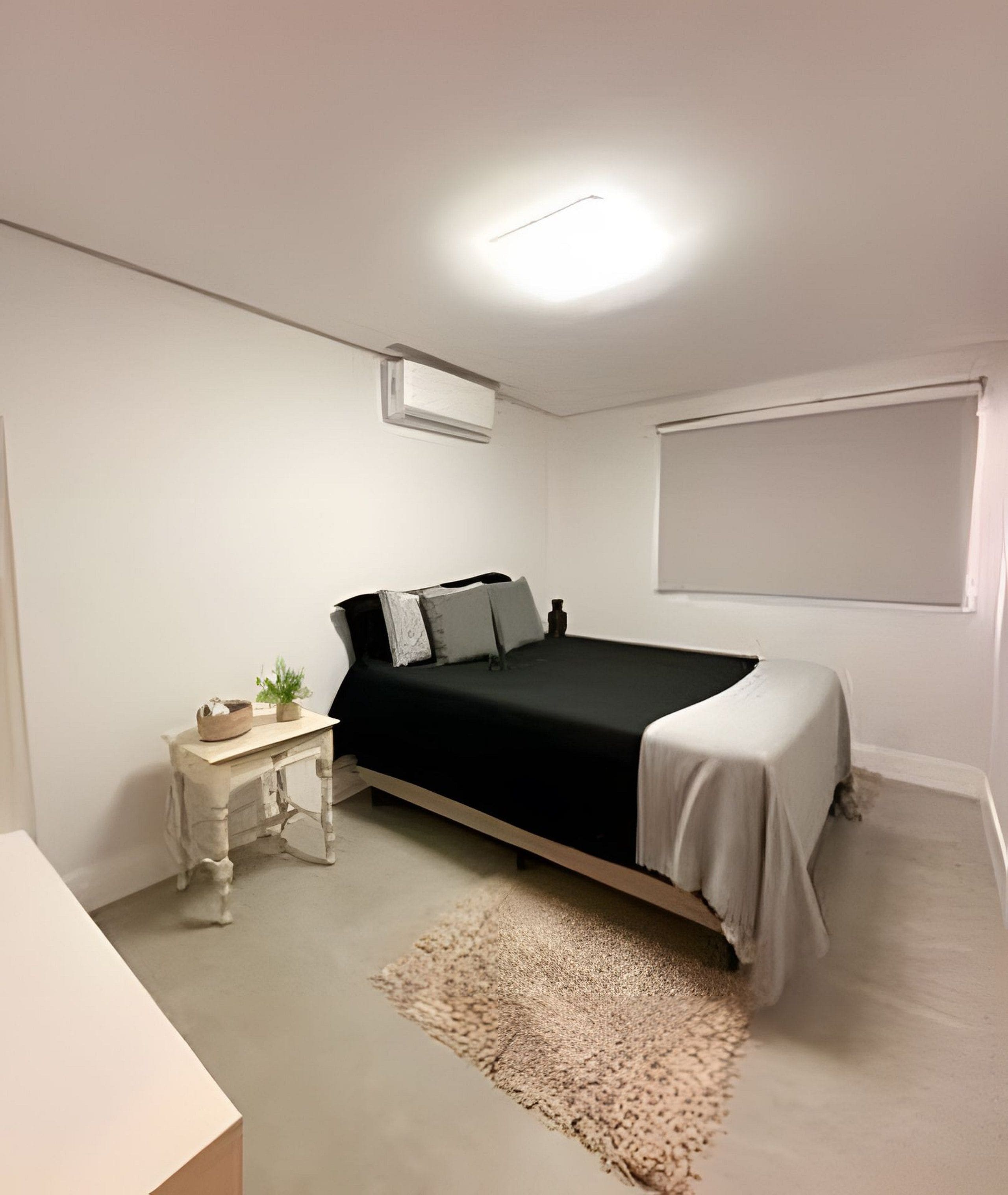 A bedroom with a bed, bedside table, and a window.