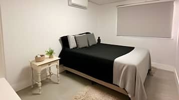 A bedroom with a bed, bedside table, and a window.