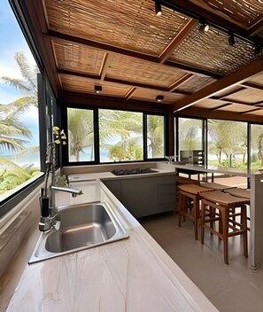 A modern kitchen with a large window, a sink, and a dining area with wooden furniture.