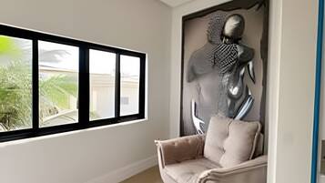 Un interior moderno con un ventanal grande, una silla minimalista y una escultura montada en la pared.