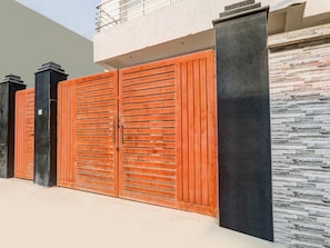 A modern building with a large, double wooden gate and a stone wall. - Saver Double bhu iit Mahamanpuri (Varanasi)