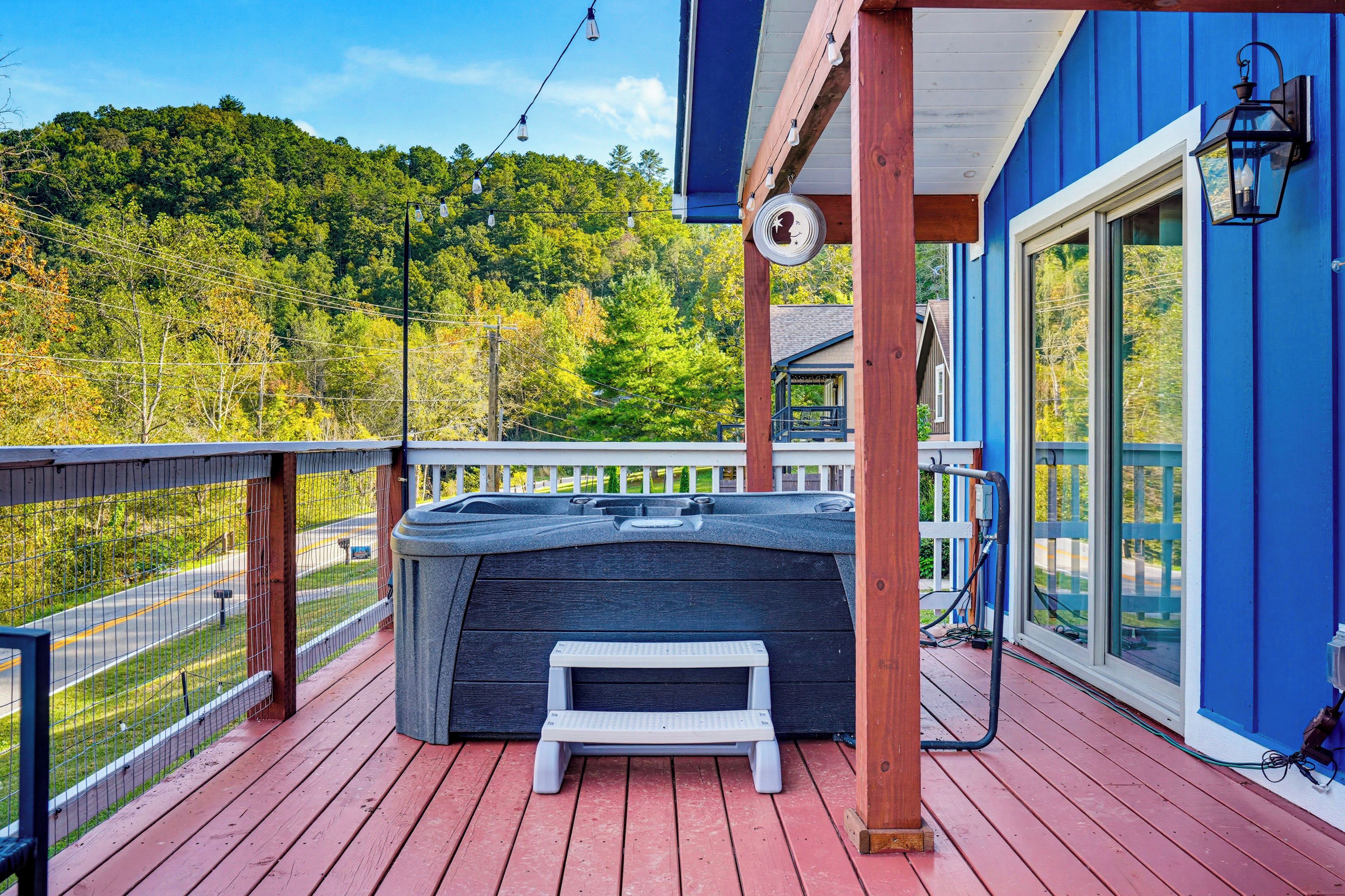 A hot tub on a wooden deck with a view of a forested area.