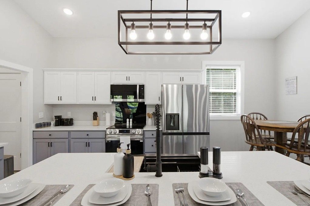 A modern kitchen with white cabinets, stainless steel appliances, and a dining area with a table set for four.