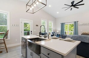 Een moderne keuken met een centraal eiland, een eethoek en een zithoek met een bank en een plafondventilator.