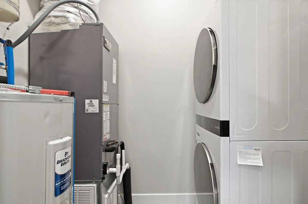 A laundry room with industrial equipment, including a large gray machine and a white machine with a label.