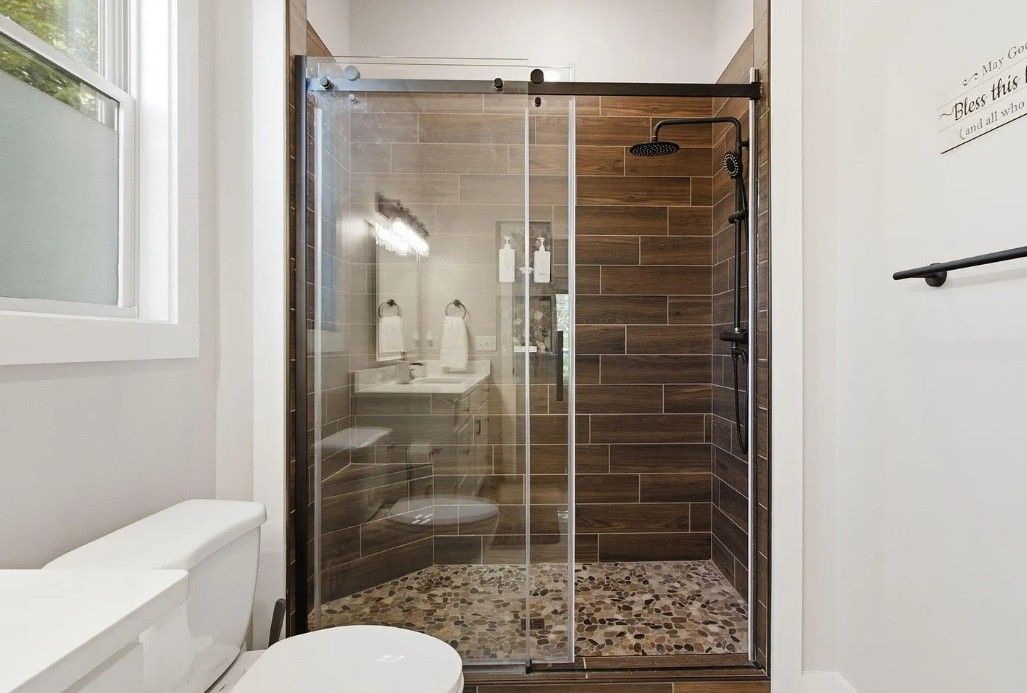 A modern bathroom with a glass-enclosed shower, a white toilet, and a sink.