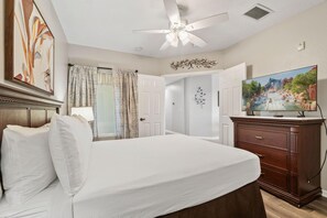A hotel room with a bed, a television, a ceiling fan, and a decorative wall piece. - 4507 Spacious 3/2 Resort Condo Near Disney (Orlando)