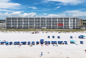 A multi-story hotel with balconies, a beach in front, and several umbrellas. - SD 303: Sea La Vie 303 - Your Gulf-Front Escape (Fort Walton Beach)