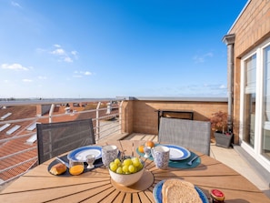 Eine Dachterrasse mit einem Frühstückstisch, komplett mit Brot, Obst und Getränken.