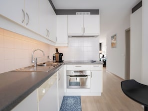 Eine moderne Küche mit weißen Schränken, einer Edelstahl-Spüle und einem eingebauten Backofen.