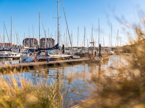 Ein Yachthafen mit mehreren vertäuten Booten, blauem Himmel und Gebäuden im Hintergrund.
