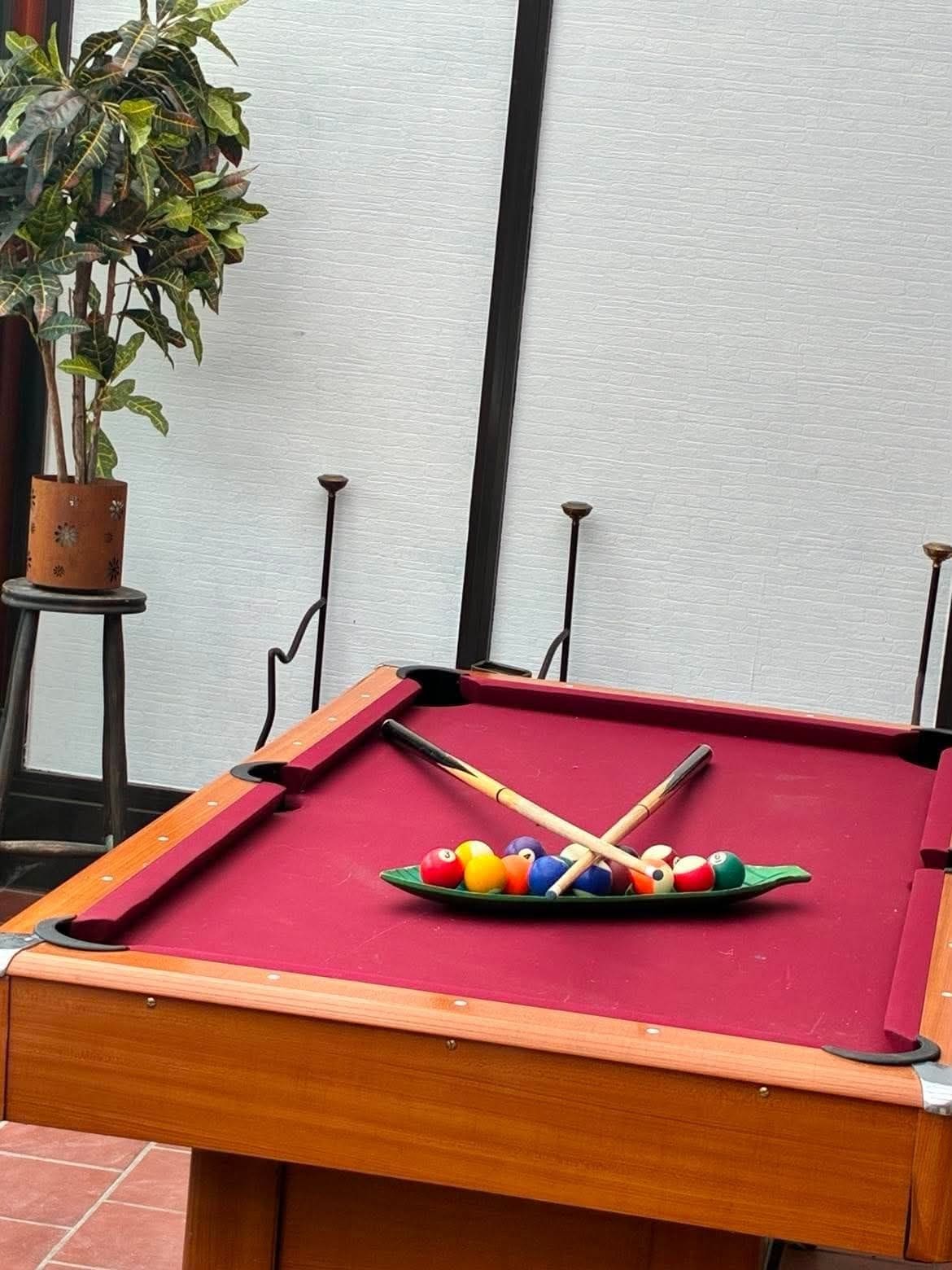A pool table with a green cloth, a set of pool cues, and a rack of billiard balls.