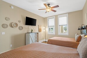 Ein Schlafzimmer mit zwei Betten, einem Deckenventilator, einem Fernseher und dekorativen Wandplatten.