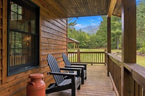 A wooden cabin with a porch, two Adirondack chairs, and a red pot on the deck. - Luxury Home|Steps from Whiteface|Near Lake Placid (Wilmington)