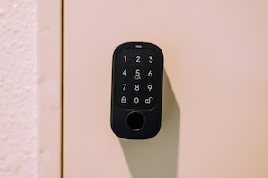 Un clavier numérique noir fixé sur un mur de couleur beige.